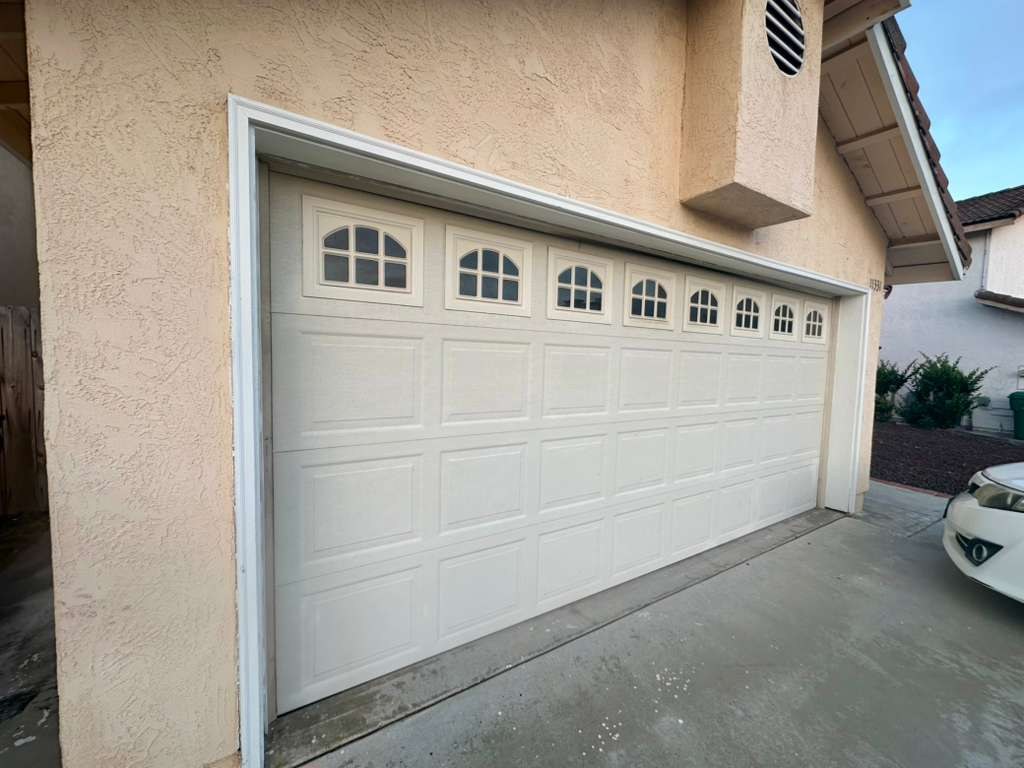 An almond raised-panel garage door with arched windows