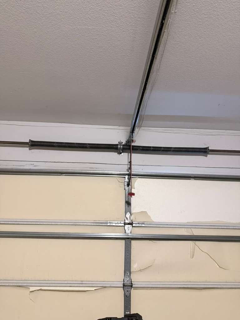 A broken torsion spring and damaged garage door panels
