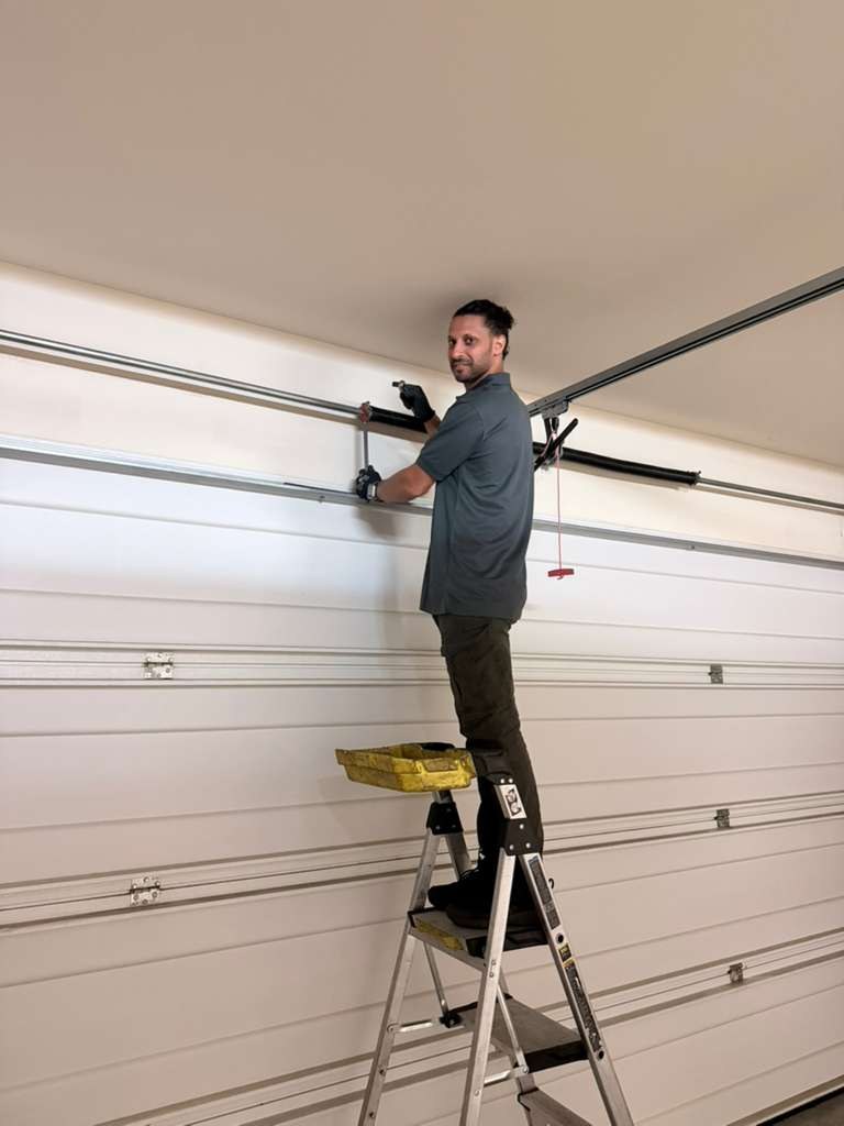 A technician servicing the torsion spring on a garage door