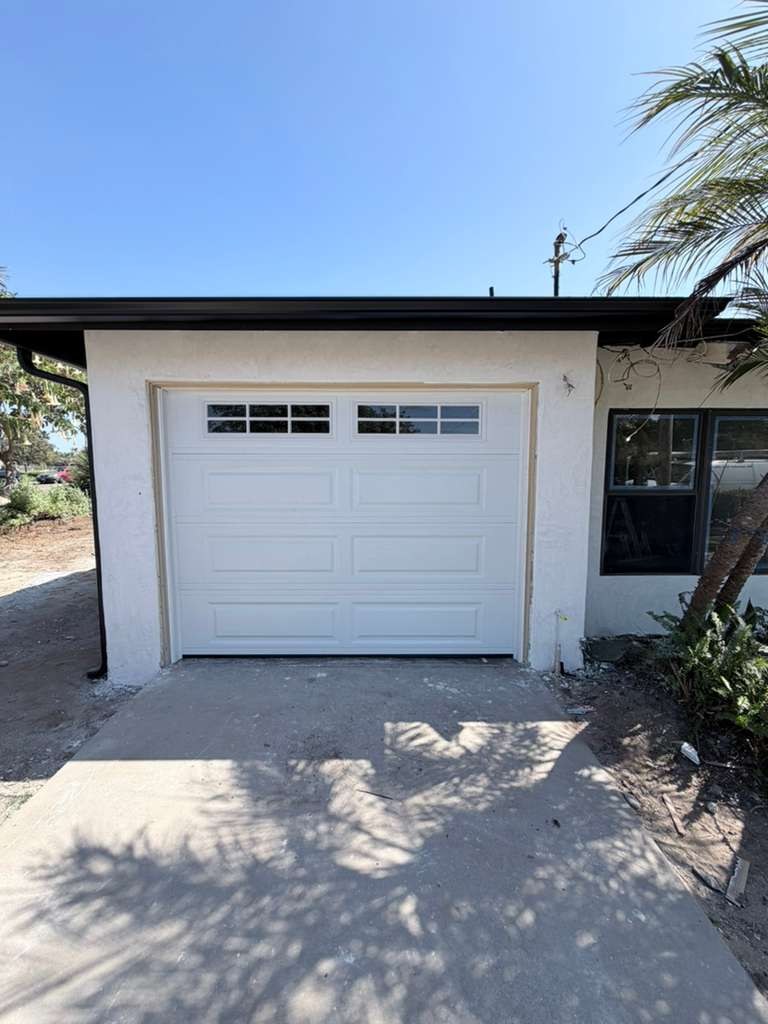 A white raised-panel single garage door with windows